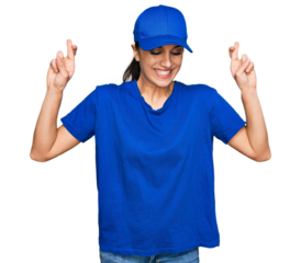 Young hispanic girl wearing delivery courier uniform gesturing finger crossed smiling with hope and eyes closed. luck and superstitious concept.