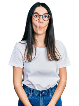 Young hispanic woman wearing casual clothes and glasses making fish face with lips, crazy and comical gesture. funny expression.