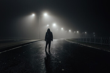 Sad man alone walking along the alley in night foggy road