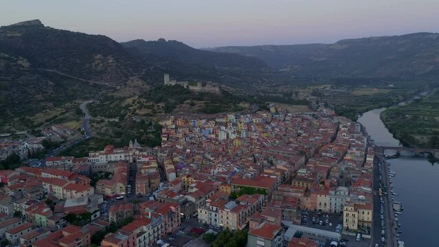 Aerial drone view of Bosa historic city colorful houses and castle with Temo river and historic bridge at sunset in Sardinia, Italy