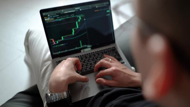 man businessman investor trader trades on bitcoin crypto exchange during a bull market, close-up hands typing on laptop keys, chart and candles of crypto market, investment