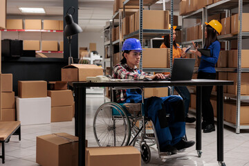 Shipment warehouse worker in wheelchair processing customer order on laptop. Young asian storehouse...