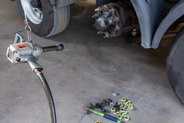 Compressed air tool to remove wheel bolts in a tire shop, with a truck with a wheel removed.