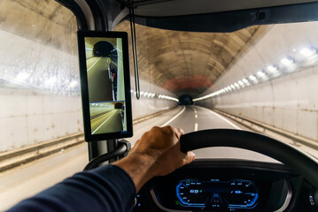 View from the driving position of a truck of the interior of a highway tunnel and a screen as a...