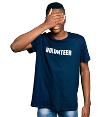Fototapeta premium Young african american man wearing volunteer t shirt smiling and laughing with hand on face covering eyes for surprise. blind concept.