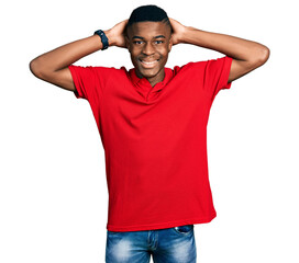 Fototapeta na wymiar Young african american man wearing casual red t shirt relaxing and stretching, arms and hands behind head and neck smiling happy