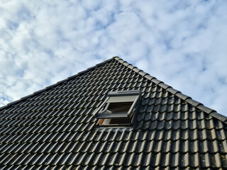 Fototapeta na wymiar Open roof window in velux style with black roof tiles.