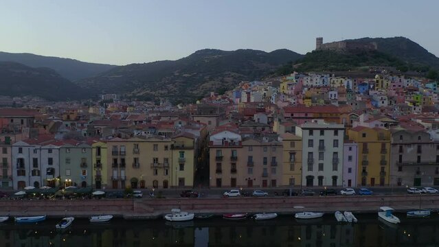 Aerial drone view of Bosa historic city colorful houses with Temo river and historic bridge at sunset in Sardinia, Italy