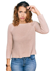 Fototapeta premium Beautiful young caucasian woman wearing casual sweater worried and stressed about a problem with hand on forehead, nervous and anxious for crisis