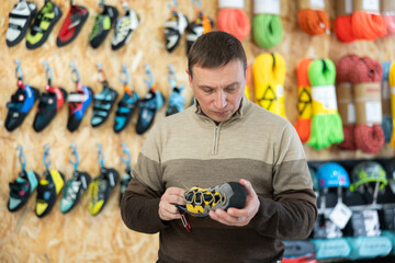 Man meticulously chooses climbing shoes in a sports store