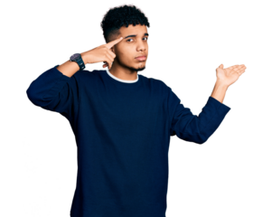 Young african american man wearing casual clothes confused and annoyed with open palm showing copy space and pointing finger to forehead. think about it.