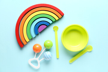 Educational toy blocks, baby rattle and feeding set on blue background