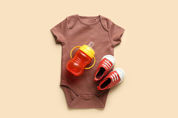 Cotton clothes with baby bottle and shoes on orange background
