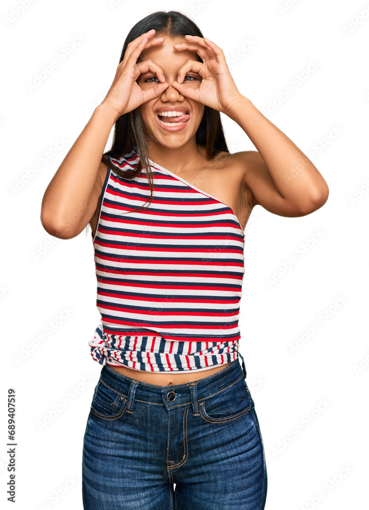 Poster beautiful hispanic woman wearing casual clothes doing ok gesture like binoculars sticking tongue out