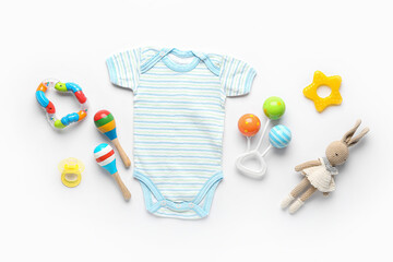 Cotton baby clothes with rattles and knitted toy on white background