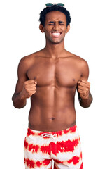 Fototapeta premium African handsome man wearing swimsuit and sunglasses excited for success with arms raised and eyes closed celebrating victory smiling. winner concept.