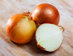 Raw whole and sliced yellow onions on wooden background