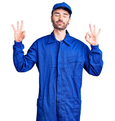 Young hispanic man wearing painter uniform relax and smiling with eyes closed doing meditation gesture with fingers. yoga concept.