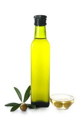 Glass bottle with olive oil, leaves and bowl on white background