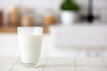 Glass of fresh milk on white tile table