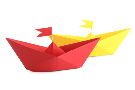 Colorful origami boats with flags on white background