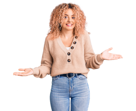 Young blonde woman with curly hair wearing casual winter jumper clueless and confused expression with arms and hands raised. doubt concept.