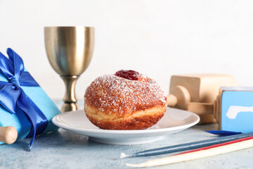 Hanukkah composition with sufganiyot, goblet, gift boxes and dreidels on blue grunge table, closeup