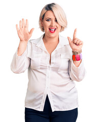 Young blonde plus size woman wearing casual shirt showing and pointing up with fingers number seven while smiling confident and happy.