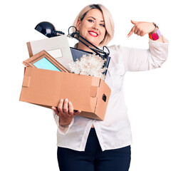 Young blonde plus size woman fired holding box pointing finger to one self smiling happy and proud
