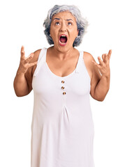 Senior woman with gray hair wearing casual clothes crazy and mad shouting and yelling with aggressive expression and arms raised. frustration concept.