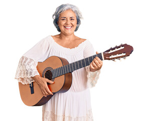 Senior woman with gray hair playing classical guitar looking positive and happy standing and smiling with a confident smile showing teeth