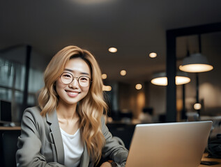 微笑むメガネをかけた女性｜ノートパソコンを使って仕事｜クローズアップポートレート