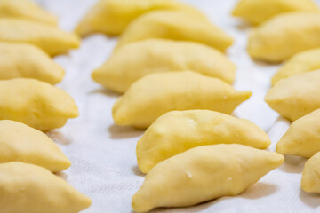 Verenik, pierogi, pierogui, perohê, Ukrainian food closeup on wooden table with wheat flour and rolling pin. 