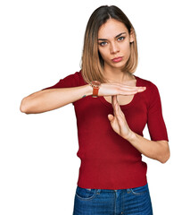 Young blonde girl wearing casual clothes doing time out gesture with hands, frustrated and serious...