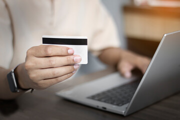 Close-up of man's hand paying online with credit card, online shopping on laptop at home, online transaction