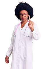 Young african american woman wearing doctor coat and stethoscope pointing with finger up and angry expression, showing no gesture