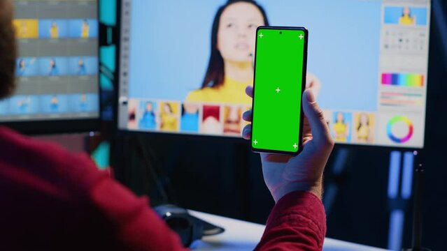 Photographer watching tutorial on mockup mobile phone to learn how to professionally enhance images quality. Photo editor following guide on green screen smartphone about using retouching software