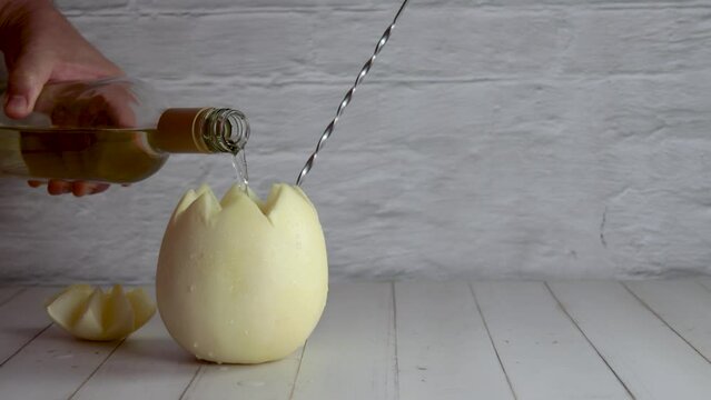 Melon with wine, melvin, preparing, cocktail, adding, white wine. On white wooden table, stirrer. Originally from Chile, summer. Typical Chilean food and drink