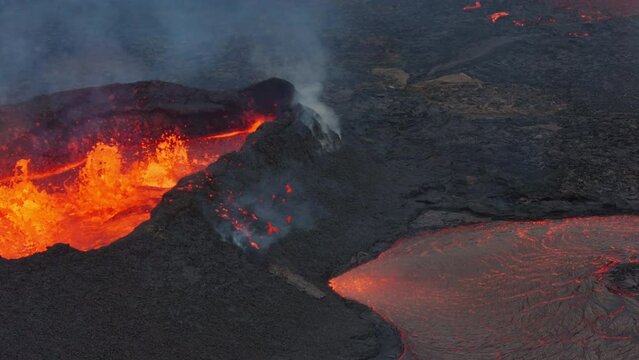 Aerial drone view over river of molten hot lava erupting from the Litli-Hrútur Iceland volcano and flows through dark rock in 2023. Tourist attraction to beautiful and dangerous disaster.