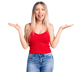 Young beautiful blonde woman wearing casual clothes celebrating victory with happy smile and winner expression with raised hands