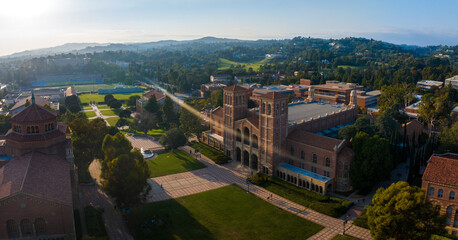 Fototapeta na wymiar Aerial view of UCLA campus bathed in golden light, showcasing Romanesque Revival and Gothic architecture amid lush greenery, with Royce Hall as the centerpiece.