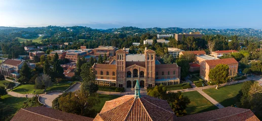 Fototapeten Aerial view of UCLA campus featuring classical architecture, red-brick buildings, green spaces, and a distinctive domed structure under a clear blue sky. © ingusk