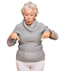 Senior grey-haired woman wearing casual winter sweater pointing down with fingers showing...