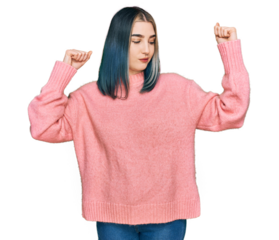 Young modern girl wearing pink wool winter sweater showing arms muscles smiling proud. fitness concept.