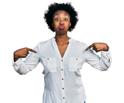 African american woman with afro hair pointing with fingers to herself puffing cheeks with funny face. mouth inflated with air, catching air.