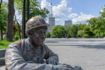 a bronze statue of worker coming out from the manhole on the ground of freedom square in kharkiv city