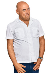 Mature middle east man with mustache wearing casual white shirt smiling looking to the side and staring away thinking.