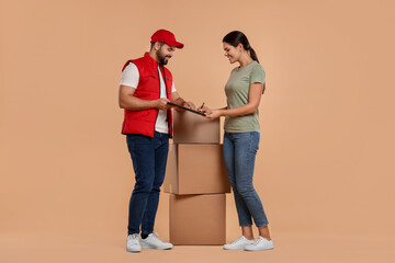 Smiling woman signing order receipt on light brown background. Courier delivery