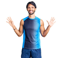 Handsome hispanic man wearing sportswear showing and pointing up with fingers number nine while smiling confident and happy.