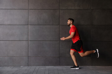 Fototapeta premium Young man running near building outdoors. Space for text